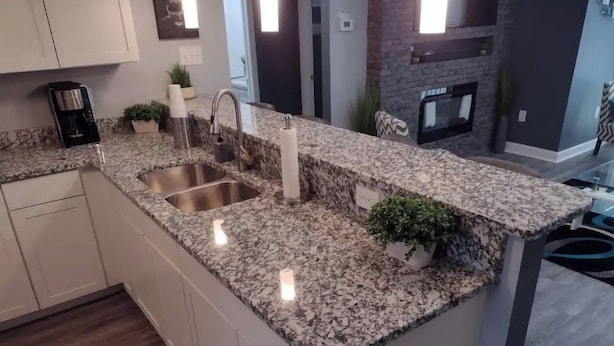 A kitchen with granite countertops, stainless steel sink, and a built-in stove.