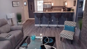 A modern living room with a sofa, a coffee table, and a bar area with stools.