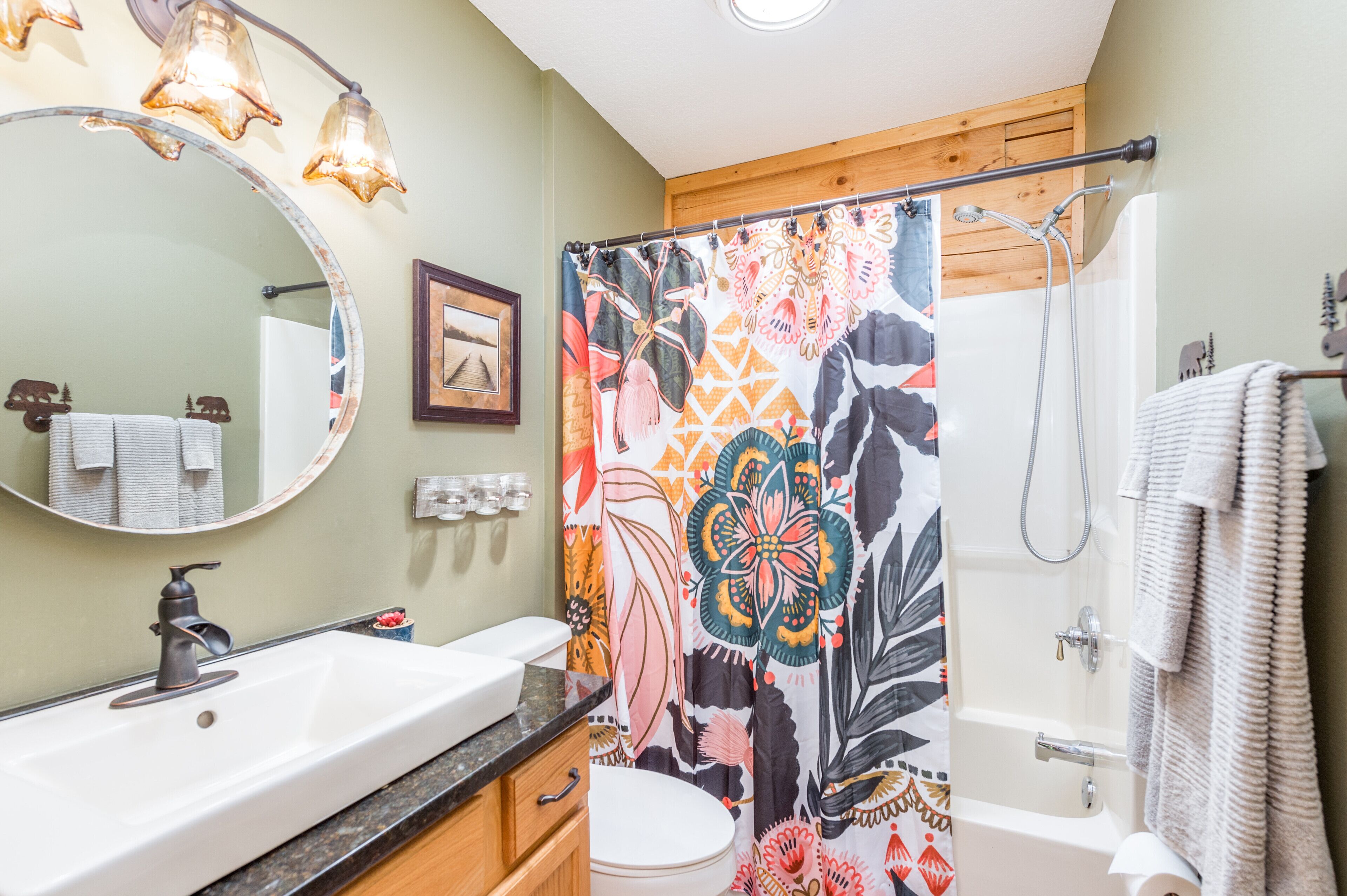A bathroom with a white sink, a mirror, a shower curtain with a floral pattern, and a towel rack.