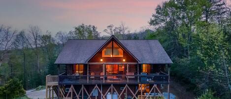 A log cabin with a balcony, surrounded by trees.