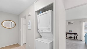 A laundry room with a front-loading washer and dryer, a mirror, and a welcome sign.