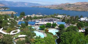 A resort with multiple swimming pools, a large building with a blue roof, and a view of a lake and mountains. - Beautiful views of Lake Chelan, scenic getaway close to downtown, Slidewaters! (Chelan)
