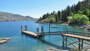 A dock extending into a calm lake with a boat moored at the end.