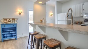 A modern kitchen with a marble countertop, white cabinets, and a blue bar cart.