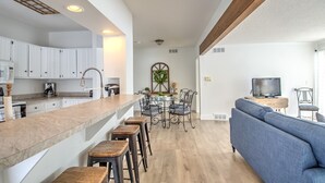 A modern kitchen with white cabinets, a wooden countertop, and a dining area with a round table and chairs.