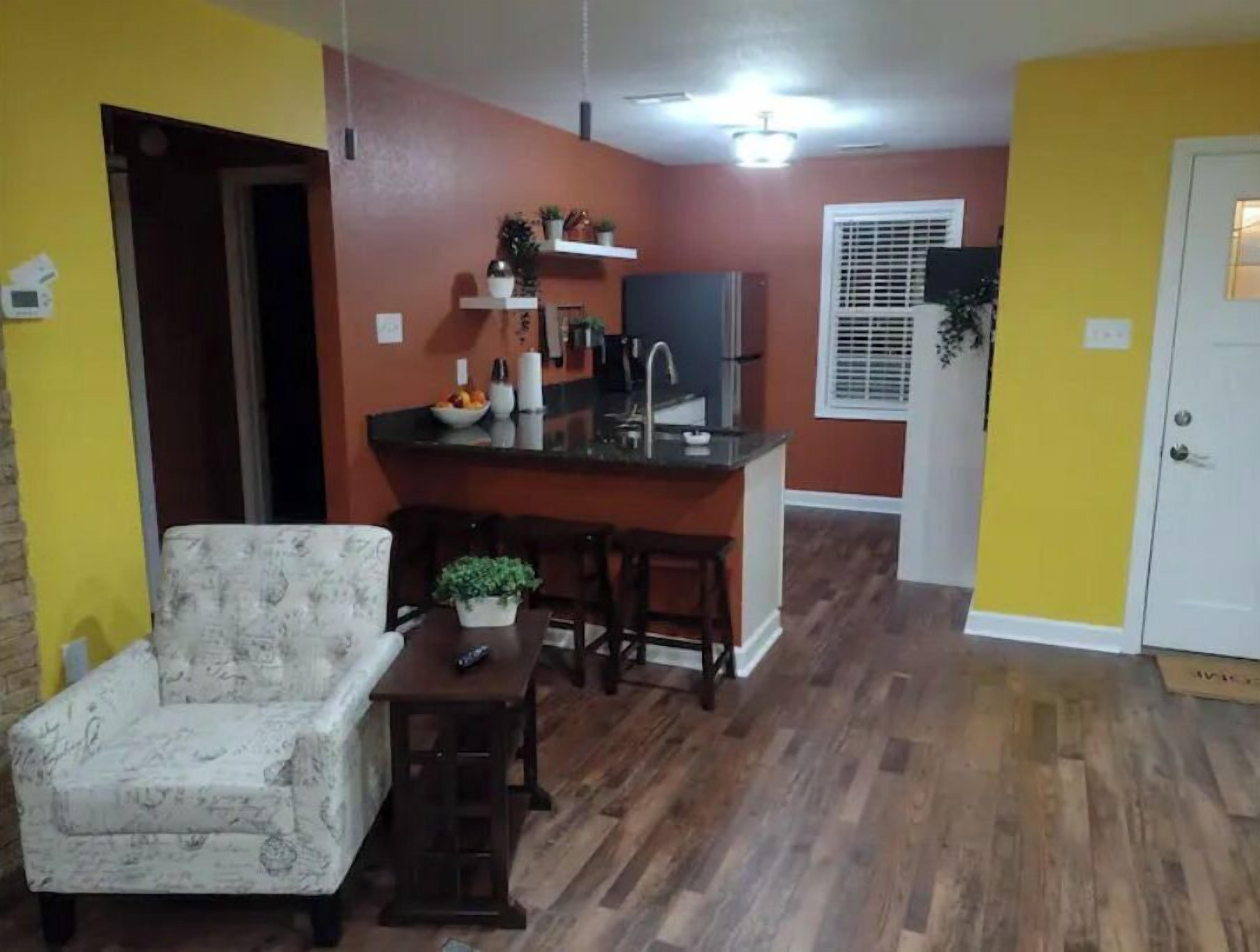 Un espace de vie compact comprenant un coin repas, une kitchenette et une porte donnant sur une autre pièce.
