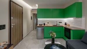 A modern kitchen with green cabinets, a wooden door, a dishwasher, and a marble countertop. - Galio Suites Airport by Airstay (Spata-Artemida)