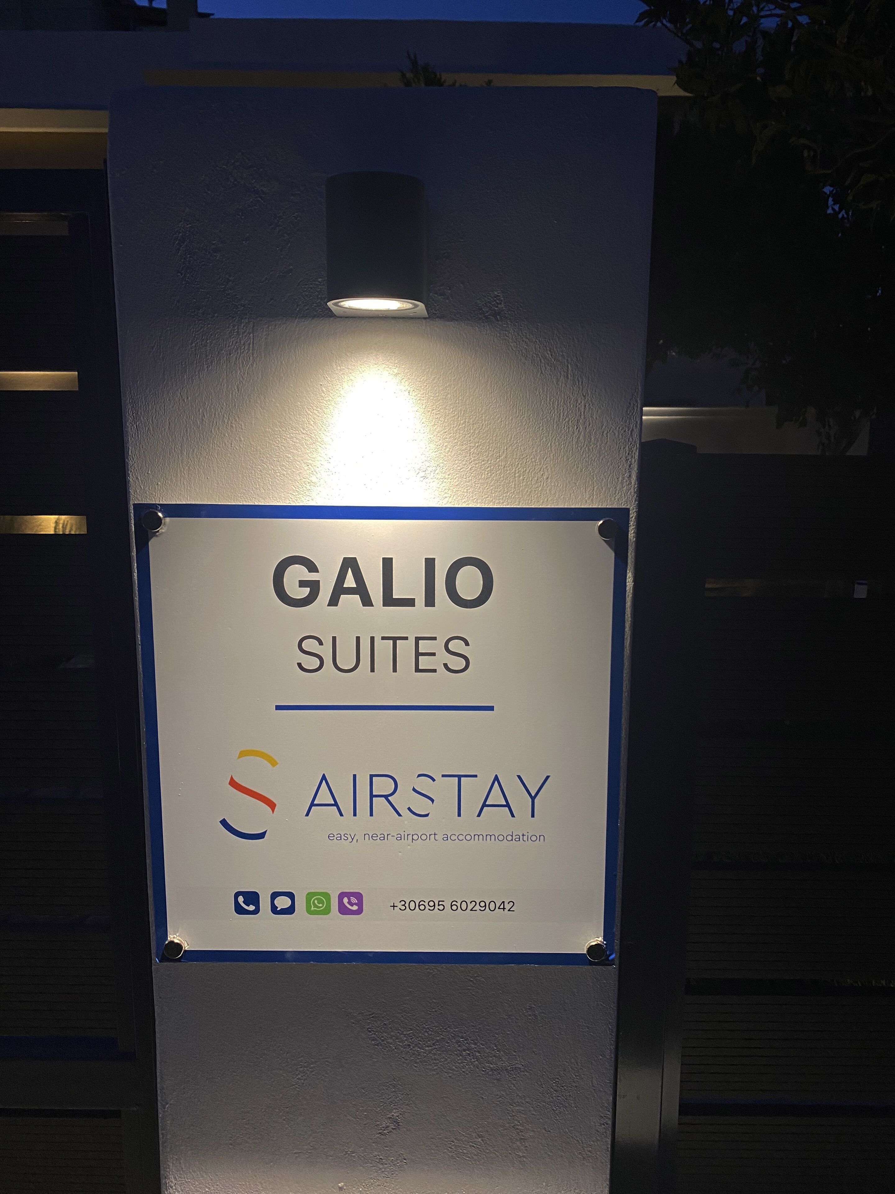 Señal de Galio Suites, que indica un alojamiento sencillo y cerca del aeropuerto, con un número de contacto.