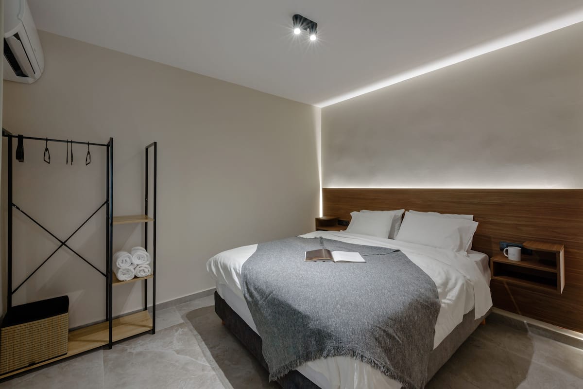 Une chambre moderne comprenant un lit, une table de chevet, une commode, une armoire et un porte-serviettes.