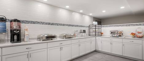 A modern kitchen with white cabinets, a coffee machine, a toaster, and a microwave.