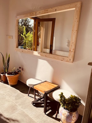 Relax in a serene outdoor space with a mirror reflecting lush surroundings, a small table, and a chair.