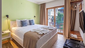 A hotel room with a bed, bedside tables, a TV, and a balcony with curtains. - Nest Gunay Otel (Kas)