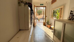 A hallway with a wooden bench, a potted plant, and a framed picture on the wall. - Nest Gunay Otel (Kas)