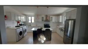 Una cocina moderna con una isla central, electrodomésticos integrados e iluminación colgante.