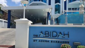 Entrada de un hotel con un cartel que dice "The Abidah by Accra Barbados".