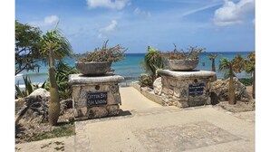 Un sendero de piedra que conduce a una playa, con un letrero que dice "Cotton Bay Sea Window".
