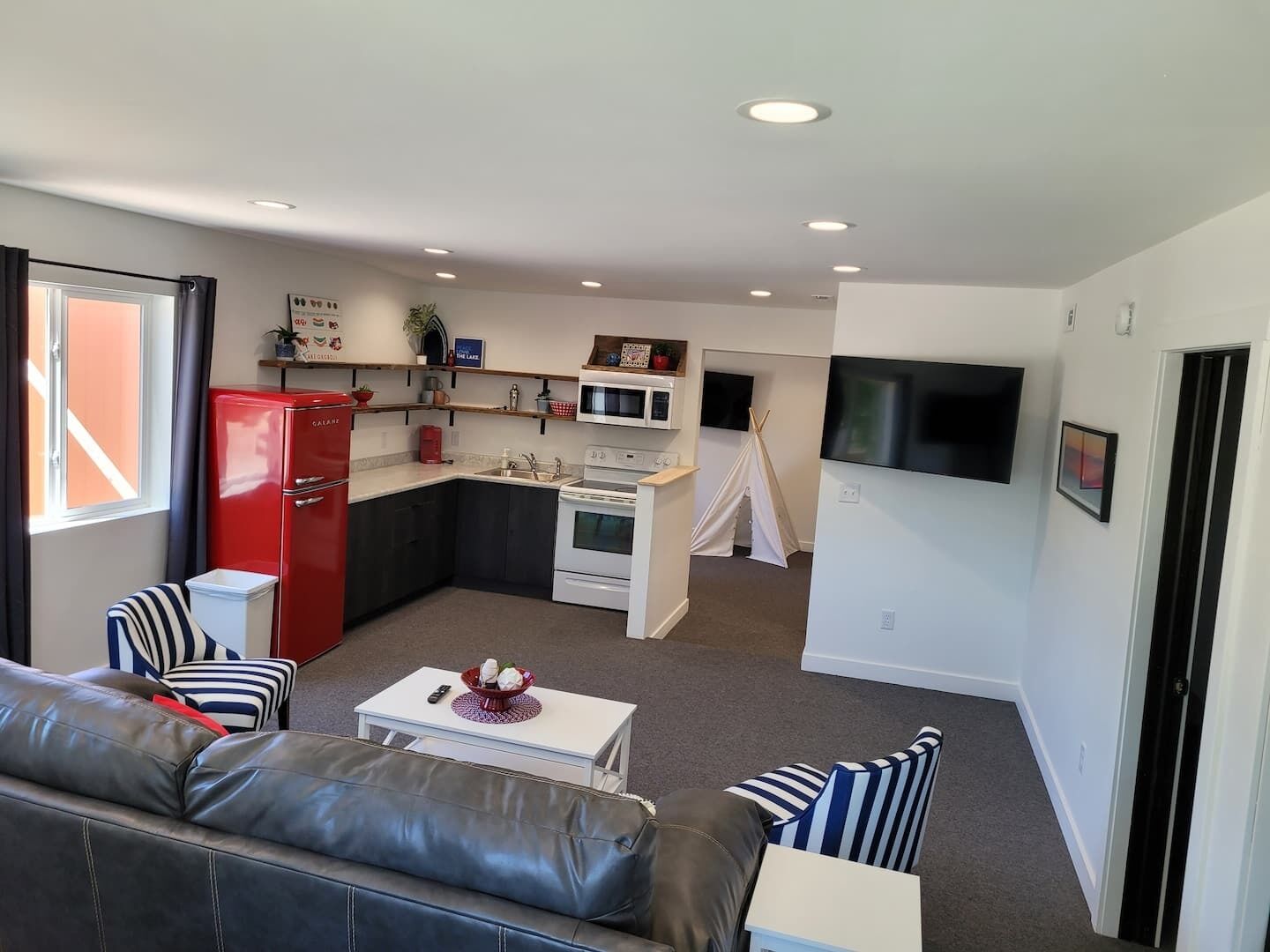 Un espacio habitable compacto con kitchenette, un sofá, un televisor y un pequeño comedor.