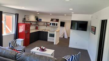 Un espacio habitable compacto con kitchenette, un sofá, un televisor y un pequeño comedor.