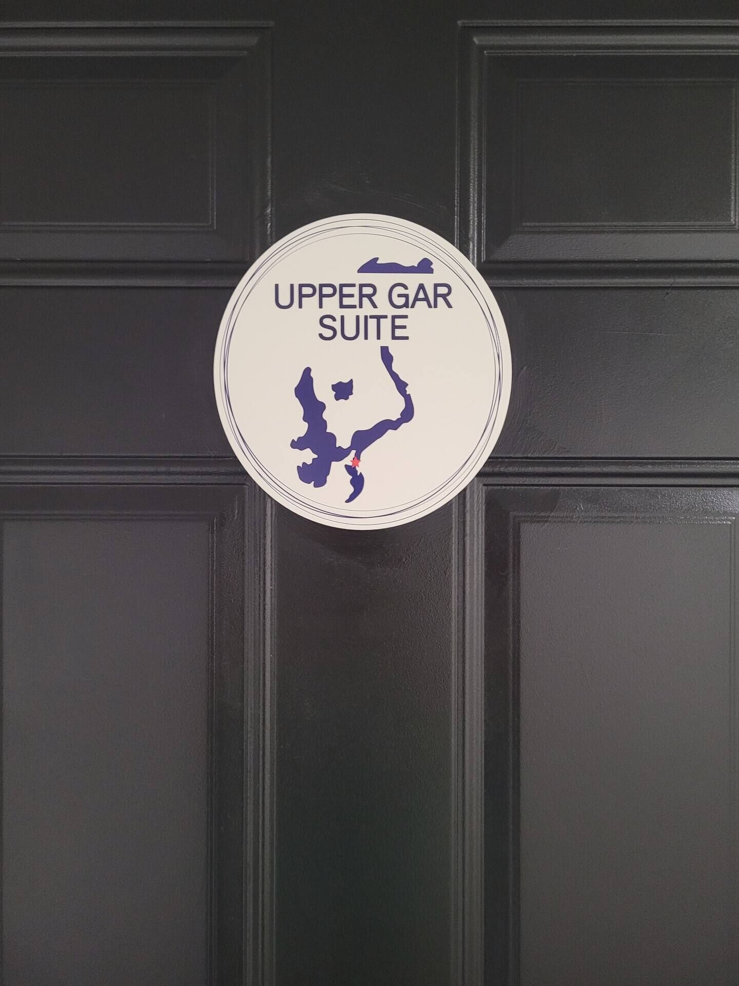 Un panneau circulaire portant l’inscription « UPPER GAR SUITE » et un plan simplifié.