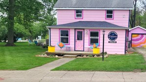 Una casa rosa con un portico, un cartello con scritto 'Benvenuti' e un cartello 'Stay-Getaway'.