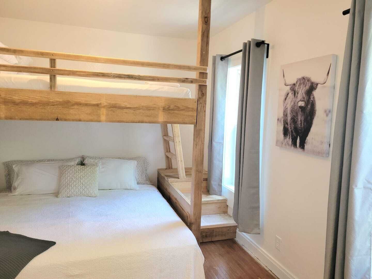 Camera con letto a castello, una testiera in legno, una scala e un dipinto di un toro sulla parete.