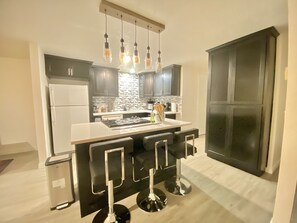 Una cucina moderna con isola centrale, sgabelli da bar e lavello in acciaio inossidabile.
