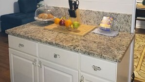 A kitchen with white cabinets, a granite countertop, a fruit bowl, and a coffee maker. - Park Ave Peacock in the heart of Cleveland TN (Cleveland)