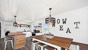 Een moderne keuken met witte houten wanden, een centraal kookeiland met krukken en hanglampen.