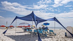 Een strand met tenten, parasols en strandstoelen.