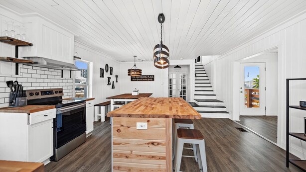 Een moderne keuken met witte kasten, een houten eiland en een roestvrijstalen fornuis.