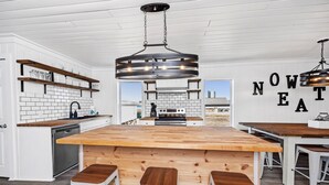 Een moderne keuken met witte kastjes, een houten eiland en een hangende lamp.