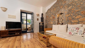 A living room with a stone wall, a television, a sofa, and a glass coffee table. - Villa O'Lucky with pool and unique tavern "konoba" (Polje (Krk))