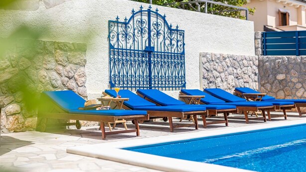 A poolside area with blue lounge chairs and a stone wall. - Villa O'Lucky with pool and unique tavern "konoba" (Polje (Krk))