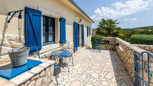 A stone-tiled patio with outdoor furniture, a stone wall, and a view of the surrounding landscape. - Villa O'Lucky with pool and unique tavern "konoba" (Polje (Krk))