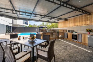 An outdoor kitchen area with a pool, dining table, and chairs. - Villa George with a heated swimming pool (Hlapa (Krk))