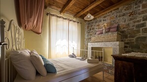 Une chambre à coucher avec un lit, une cheminée en pierre et un plafond en bois.