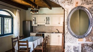 Une cuisine équipée d’une table à manger, de chaises, de placards, d’un évier et d’un miroir au mur.
