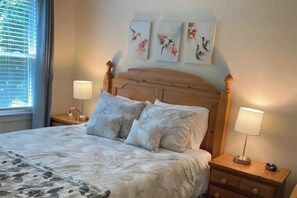 Una camera da letto con una testiera in legno, due comodini con lampade e tre quadri di uccelli appesi al muro.