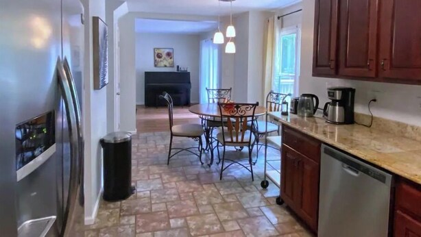 A modern kitchen with a dining area, featuring a central island, stainless steel appliances, and a view into the living room. - Highland Comfort - Private Peaceful Retreat (Chapel Hill)