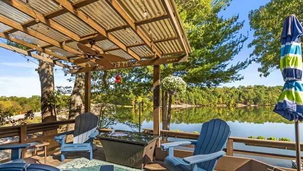 Eine Terrasse mit Adirondack-Stühlen, einem Tisch und einem hängenden Blumenkorb.