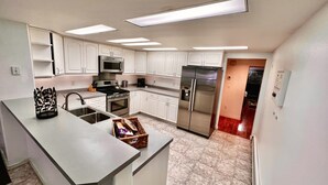 Una cocina moderna con armarios blancos, electrodomésticos de acero inoxidable y una isla central.