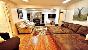 Una sala de estar con chimenea, un sofá, un sillón y una televisión.