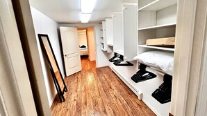 Un pasillo estrecho con suelo de madera, una puerta blanca y estanterías empotradas con espacios de almacenamiento.