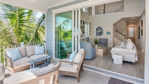A spacious living area with a sliding glass door leading to a balcony, furnished with sofas and a coffee table. - Paradise Blu by Beach Boutique Rentals (Anna Maria)