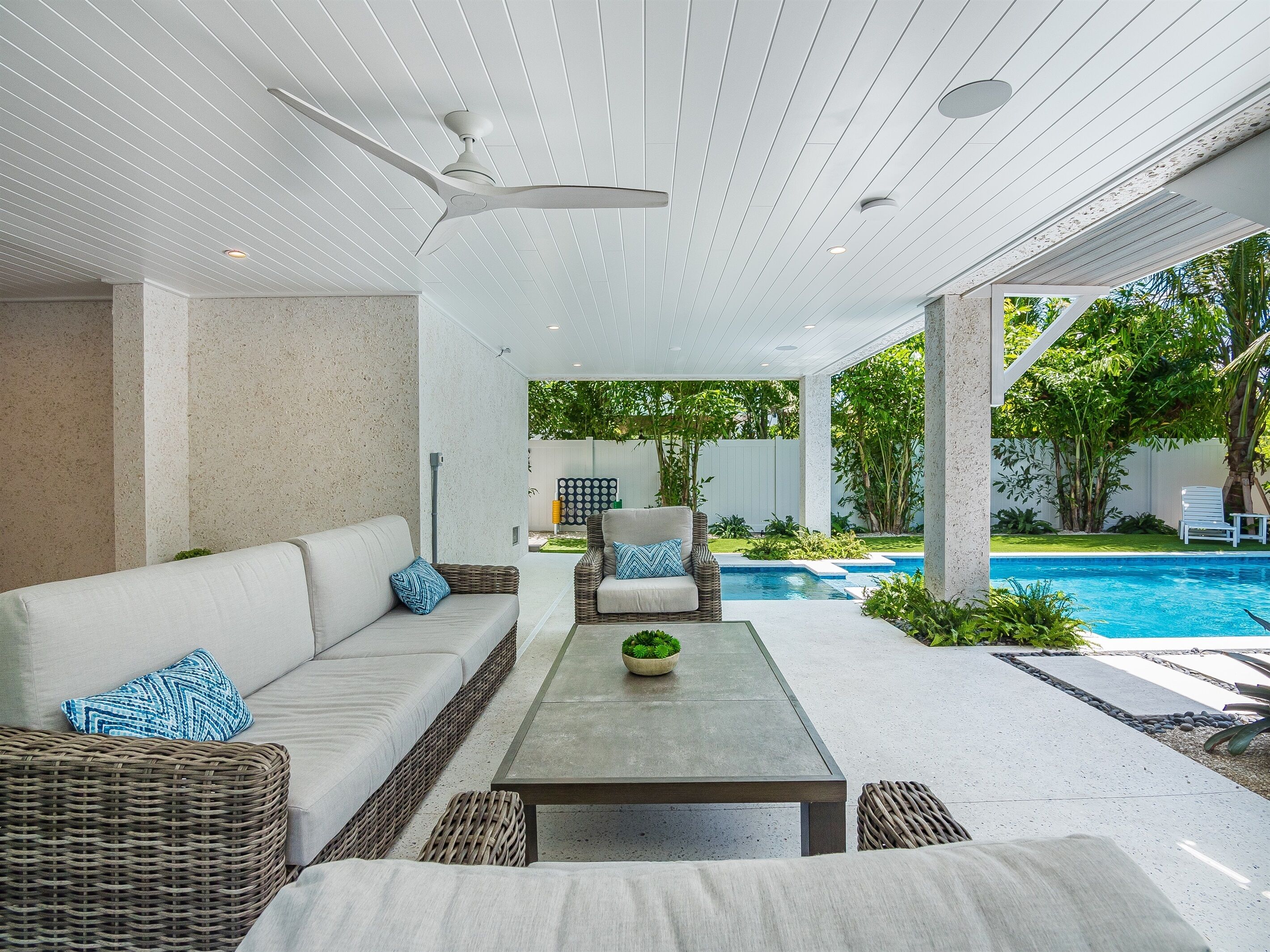 A modern outdoor living area with a pool, a sofa, a chair, and a table.