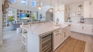A modern kitchen with white cabinetry, a marble island, and pendant lighting. - Paradise Blu by Beach Boutique Rentals (Anna Maria)