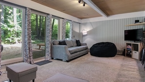 A modern living room with a grey sofa, black bean bag, and a television.