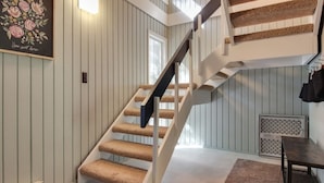 A staircase with a wooden handrail and carpeted steps, a radiator, and a framed floral artwork on the wall.