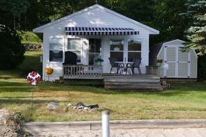 Une petite maison blanche avec un porche, un garage et une pelouse.