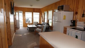Eine Küchenzeile im Blockhausstil mit Holzwänden, einem Kühlschrank, einer Mikrowelle und einer Kaffeemaschine.